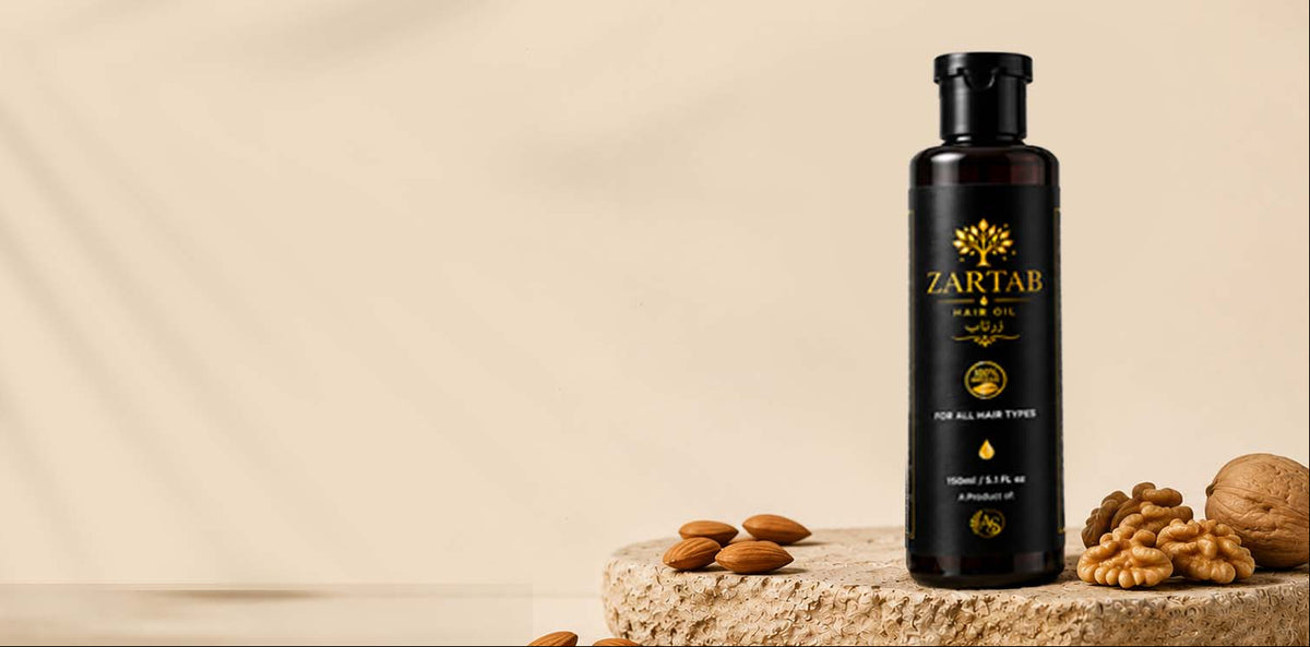 A bottle of ZARTAB Castor Oil stands on a stone slab next to almonds, walnuts, and a walnut shell, with a warm beige background and soft leaf shadows.